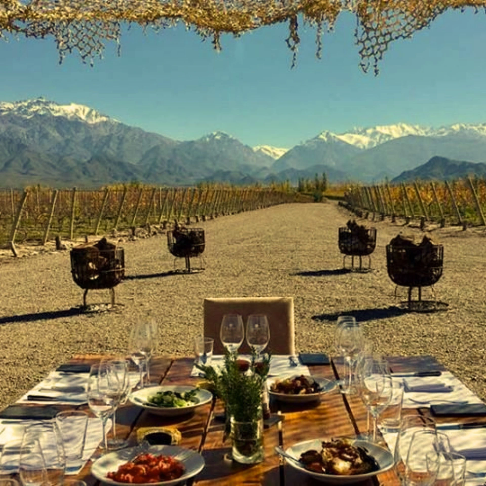 Mesa servida entre viñedos con los Andes de fondo